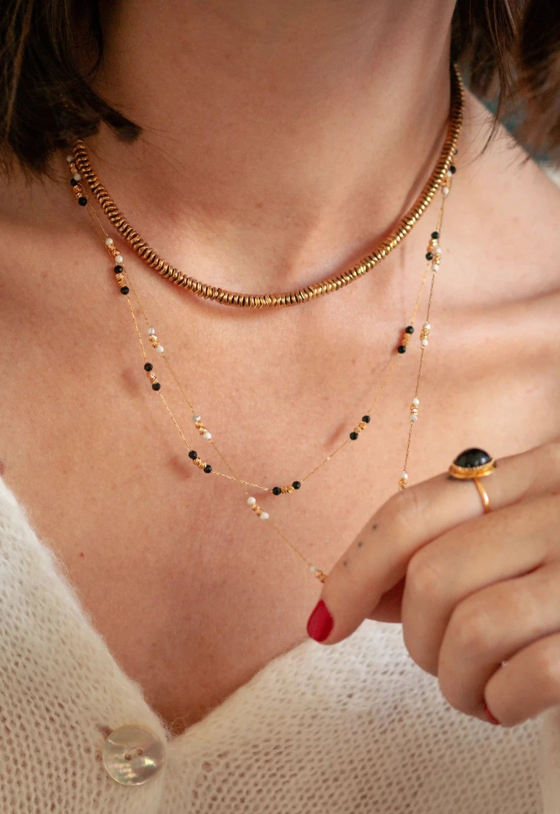 femme portant plusieurs colliers dorés et noirs au style bohème chic