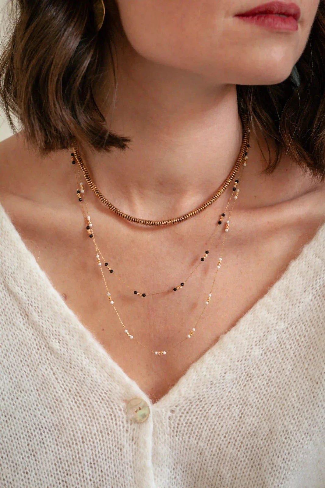 femme portant plusieurs colliers dorés et noirs au style bohème chic
