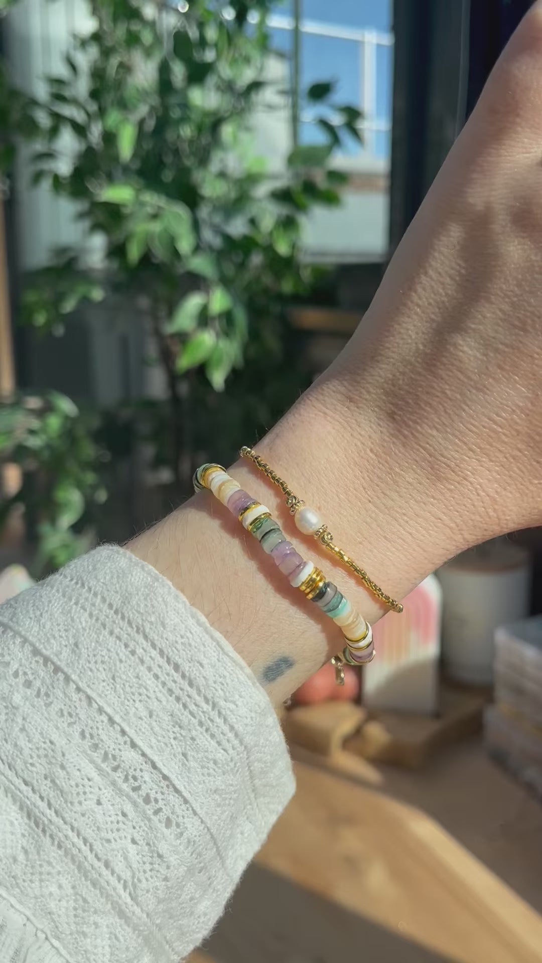 Femme portant deux jolis bracelets en perles beiges et dorées
