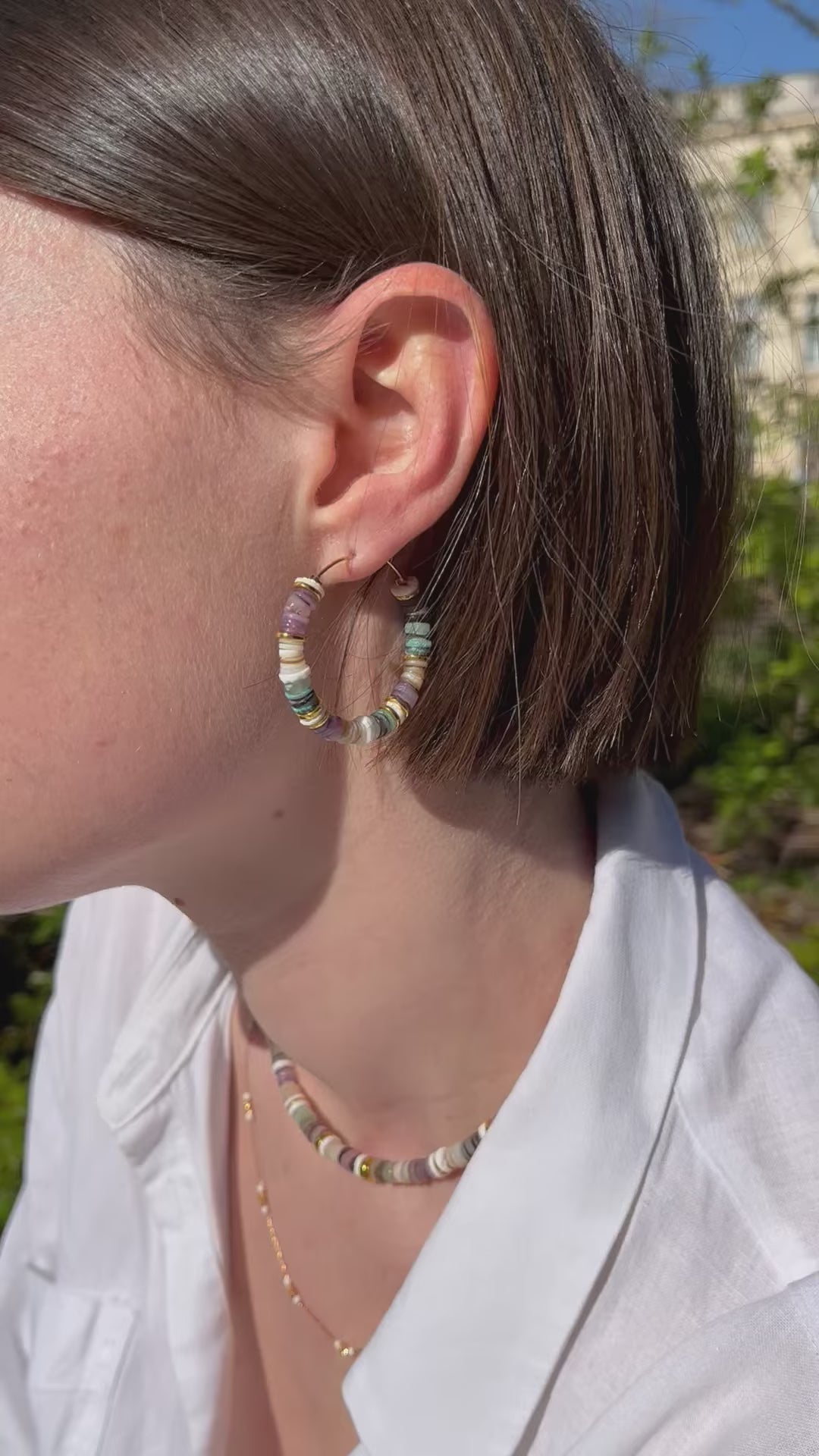 femme portant une paire de créoles en perles multicolores