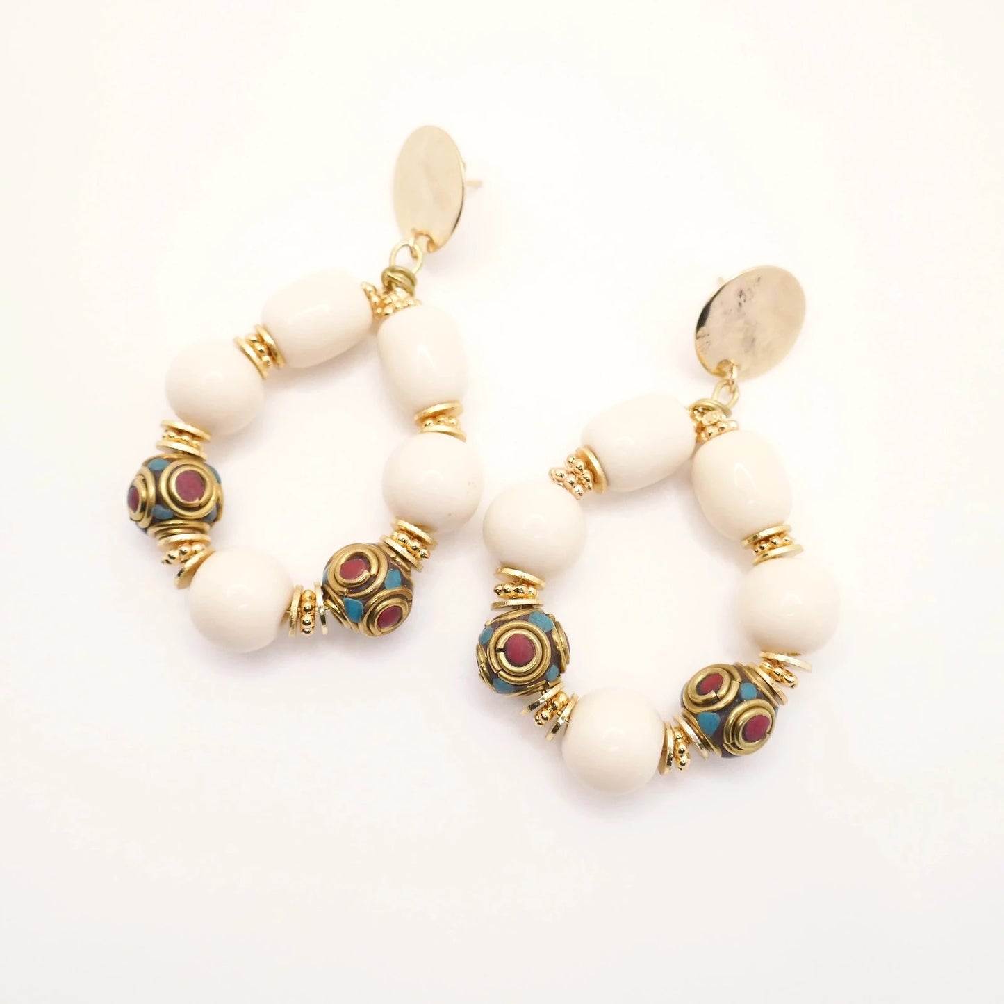 Boucles d'oreilles en grosses perles résine crème et perles tibétaines ethnique doré or imposantes pour femme sur fond blanc
