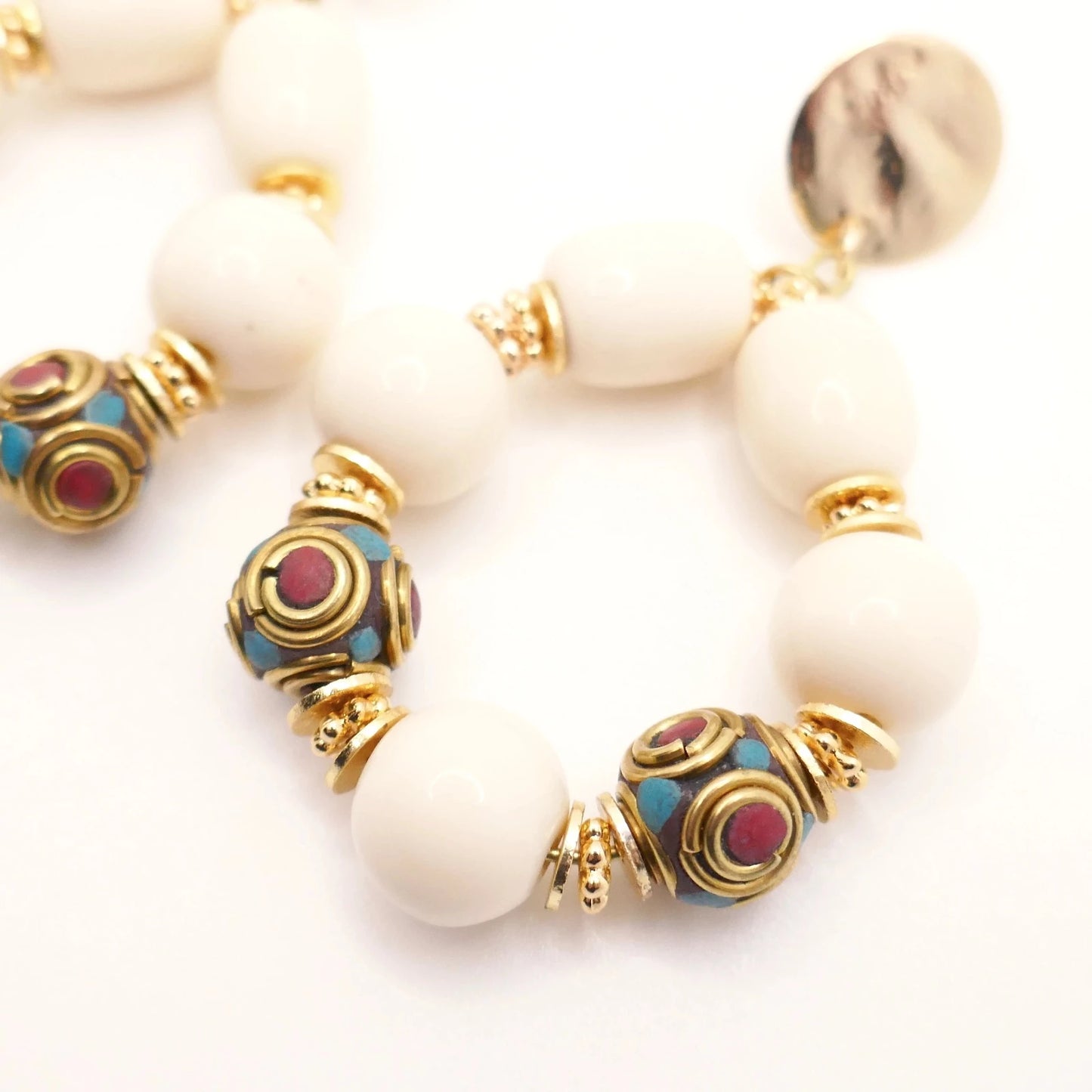 Boucles d'oreilles en grosses perles résine crème et perles tibétaines ethnique doré or imposantes pour femme sur fond blanc