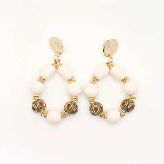 Boucles d'oreilles en grosses perles résine crème et perles tibétaines ethnique doré or imposantes pour femme sur fond blanc