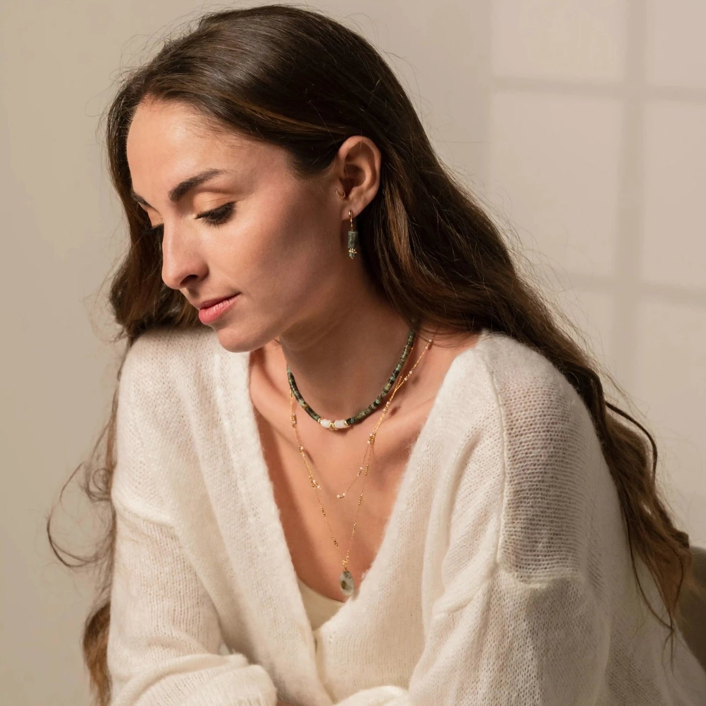 Jolie jeune femme portant des bijoux en accumulation : colliers de perles, chaines de cou, boucles d'oreilles en pierres naturelles