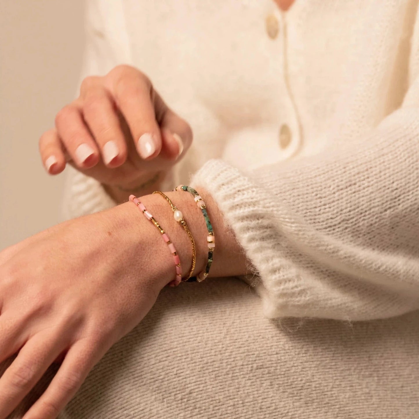 femme portant trois colliers fins en perles et pierres semi-précieuses