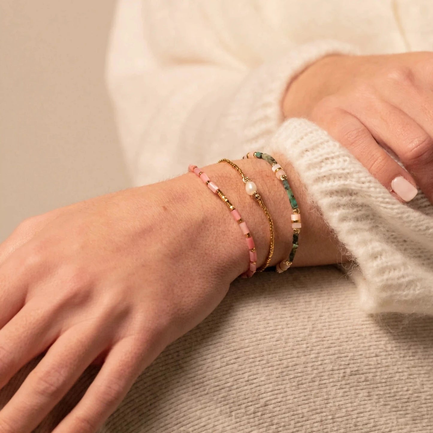 femme portant trois colliers fins en perles et pierres semi-précieuses