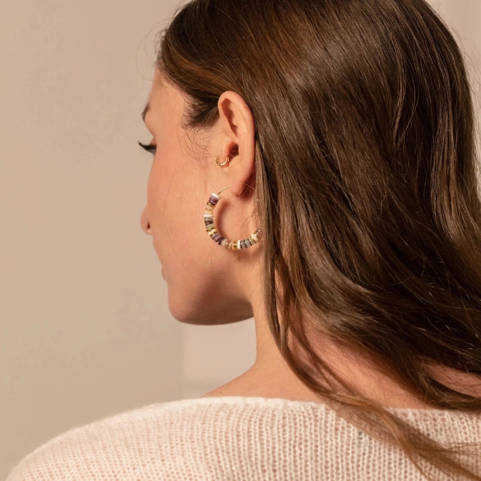 femme portant une paire de créoles en perles multicolores