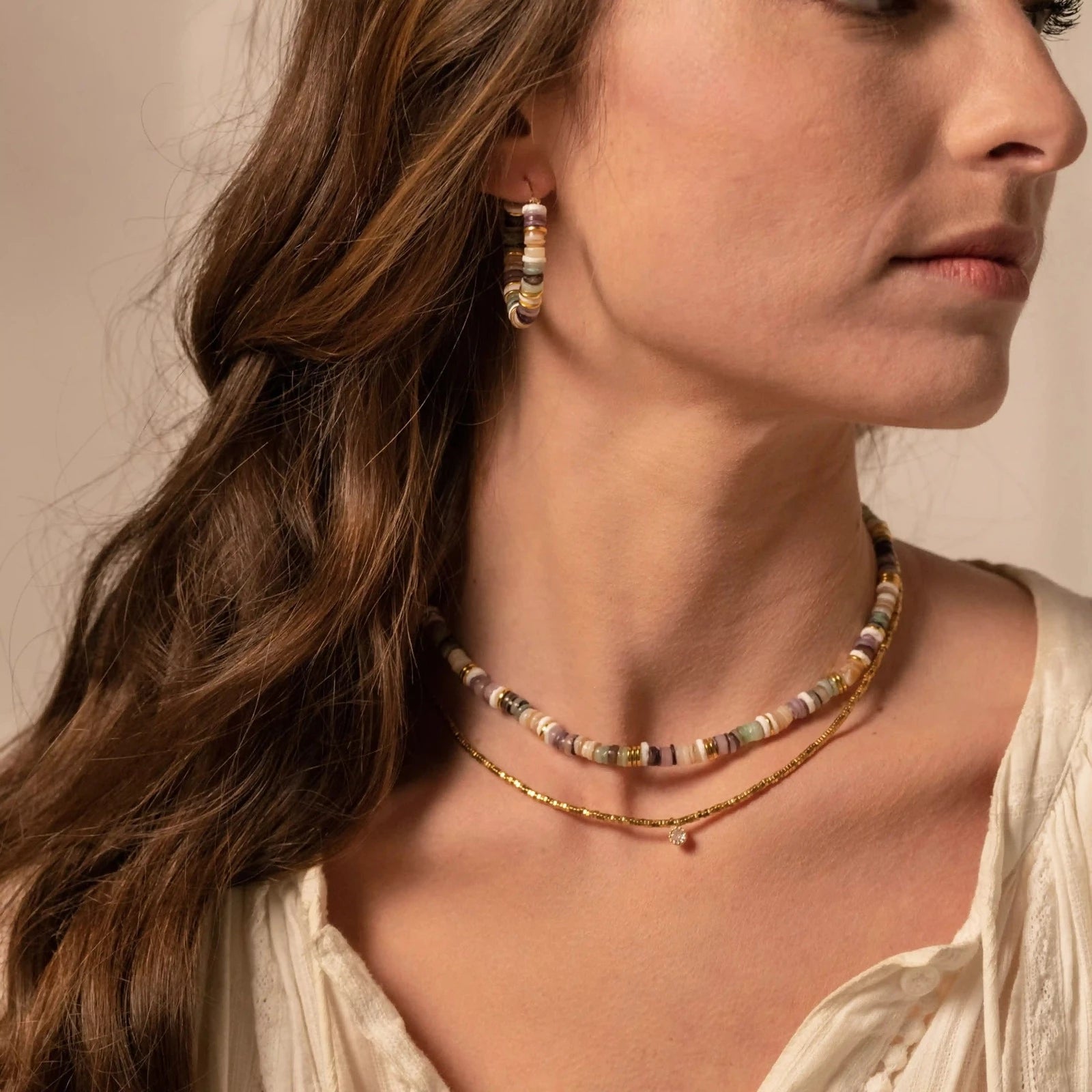 femme portant une paire de créoles en perles multicolores