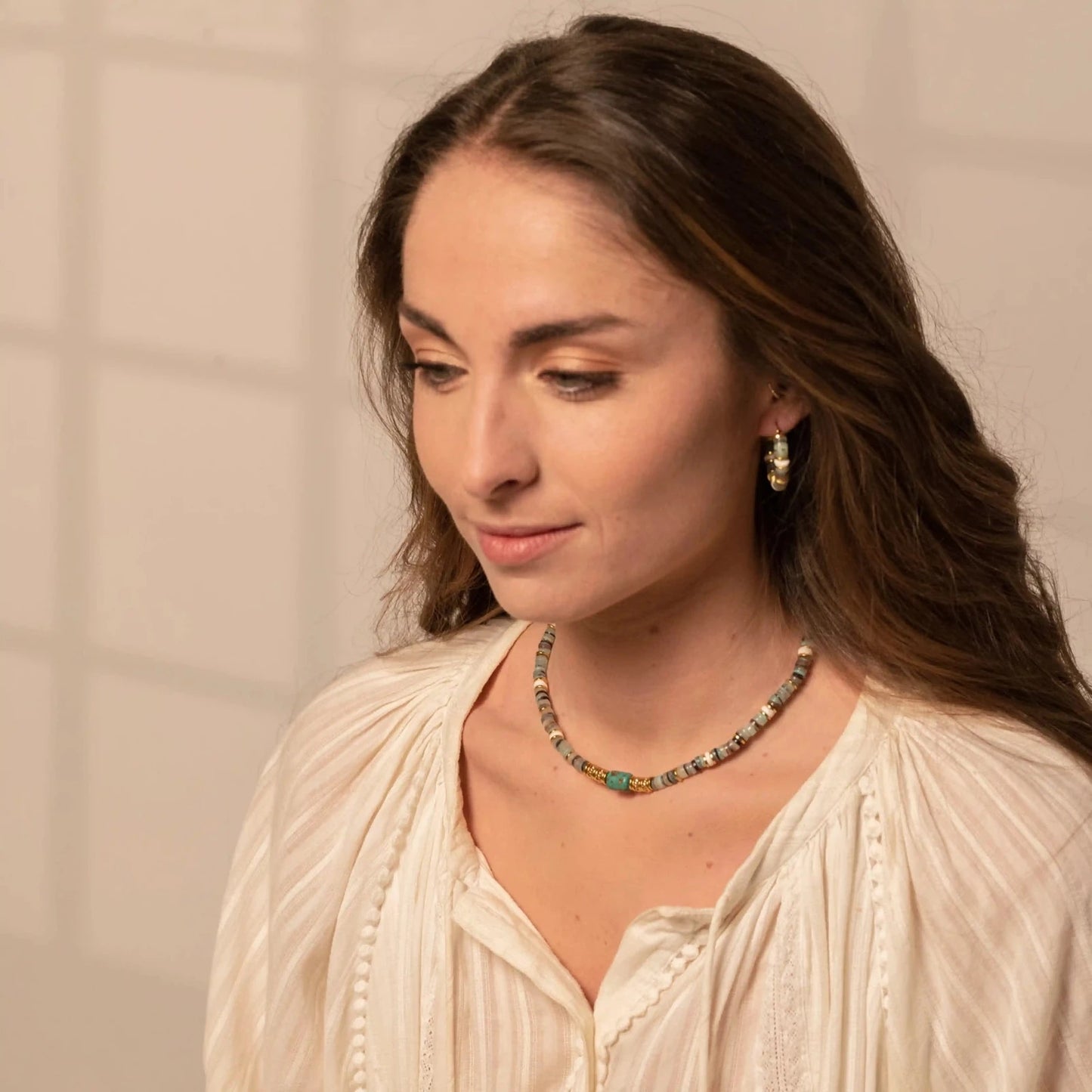 Femme portant des boucles d'oreilles créoles et un collier en perles vertes