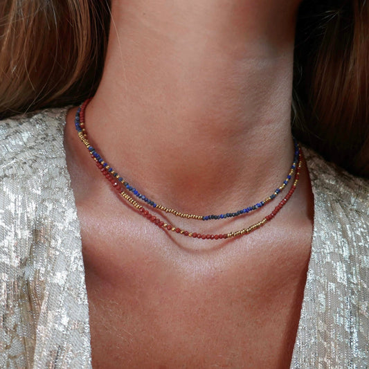femme à la peau bronzée mate portant deux colliers colorés en perles