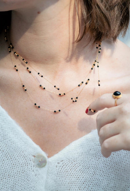 femme portant trois colliers fins en maille dorée et perles noires