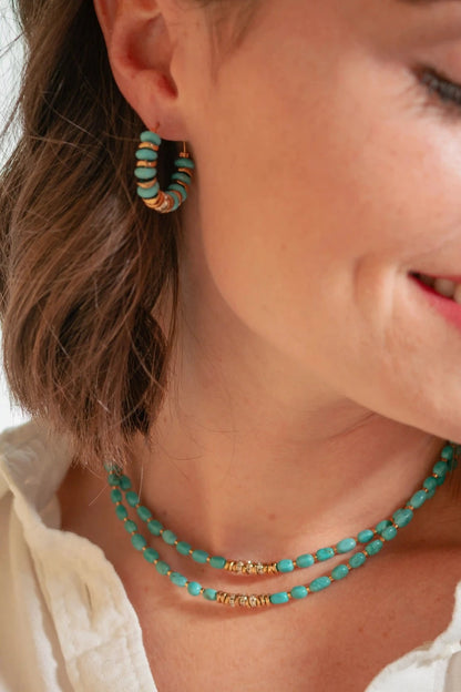 femme portant deux colliers ras de cou en perles bleues et or