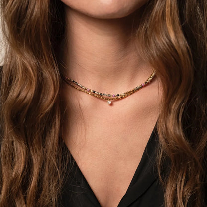 Femme au chemisier noir portant des colliers en pierres et perles fines et plaqué or 