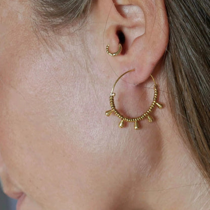 Femme aux cheveux châtains portant des boucles d'oreilles créoles en mini perles d'Hématite dorées à l'or fin