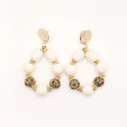 Boucles d'oreilles en grosses perles résine crème et perles tibétaines ethnique doré or imposantes pour femme sur fond blanc