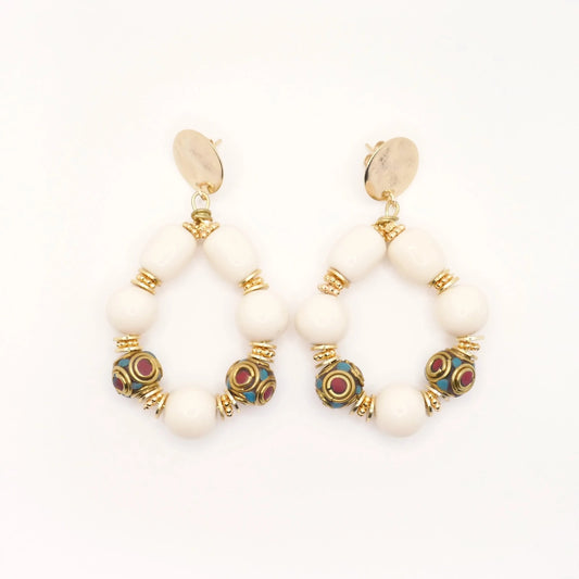 Boucles d'oreilles en grosses perles résine crème et perles tibétaines ethnique doré or imposantes pour femme sur fond blanc