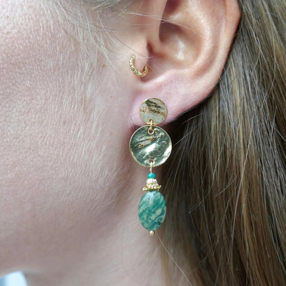 Femme rousse châtain clair portant des boucles d'oreilles fines dorées et en Jade Africaine verte