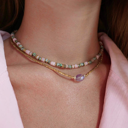 colliers femme portés en accumulation en or et pierres roses et vertes
