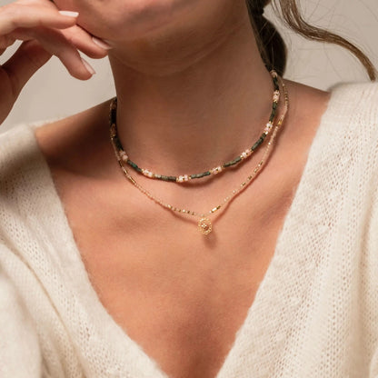 femme portant des colliers en perles dont un avec un pendentif doré en forme de croix