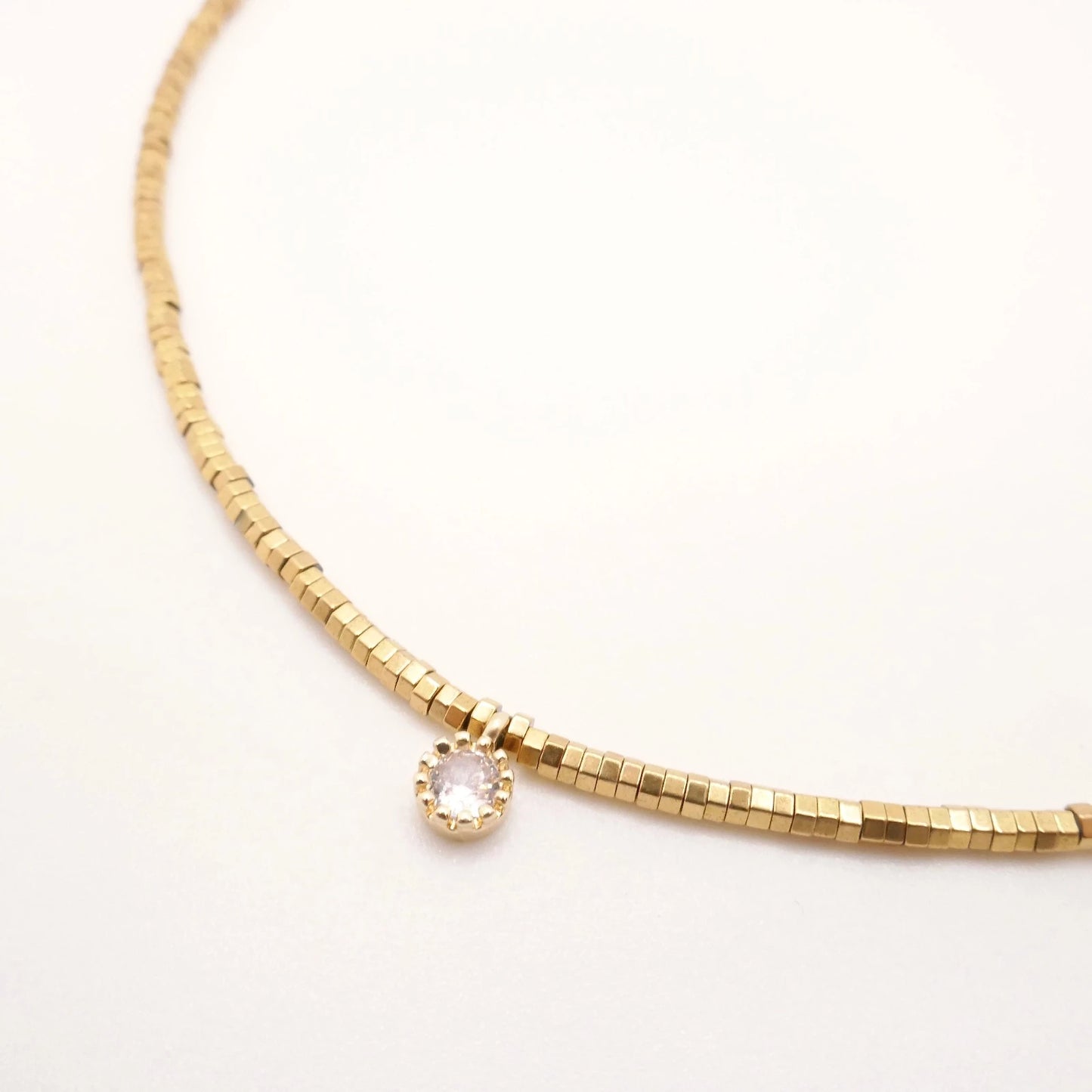 collier en perles or dorées et petit médaillon aux crénelures dorées avec un strass zircon au centre