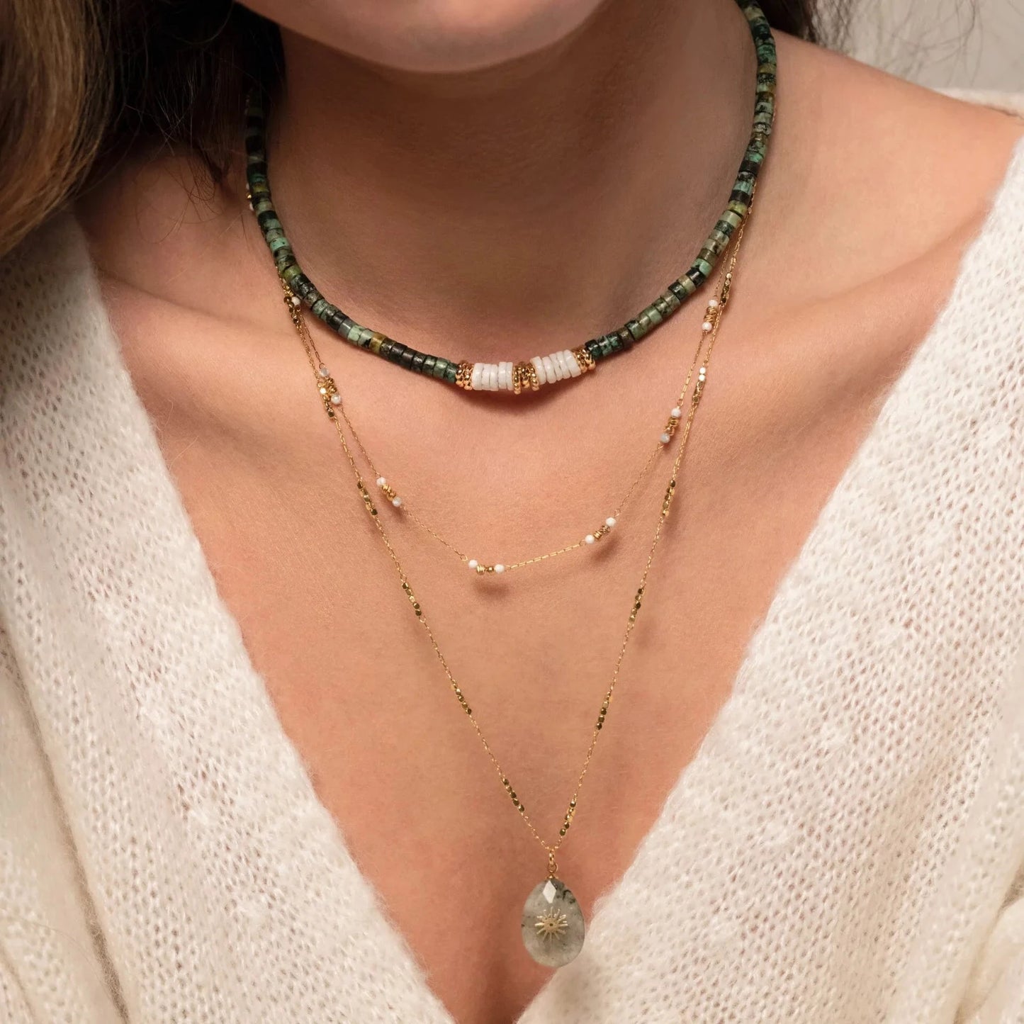 buste de femme portant trois colliers en perles et chaine or en accumulation