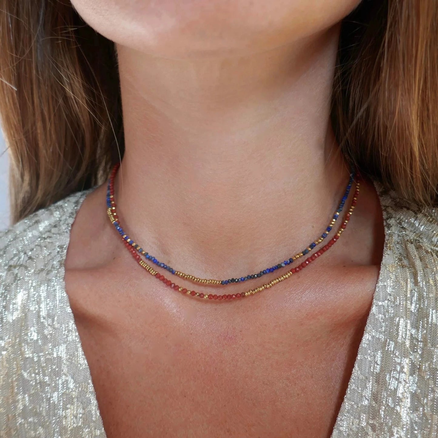 femme portant deux colliers en perles de couleur rouge et bleu et doré