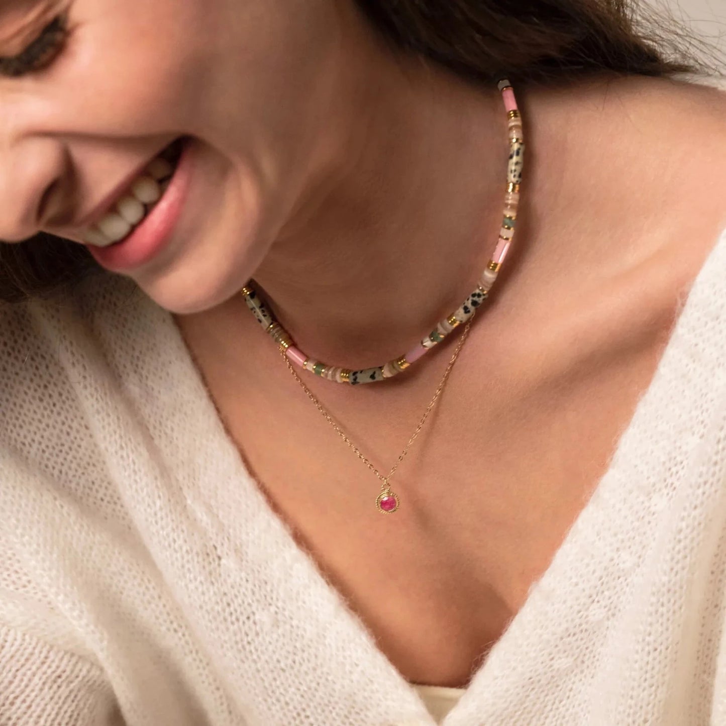 femme souriante portant des colliers fins en perles et en or en accumulation