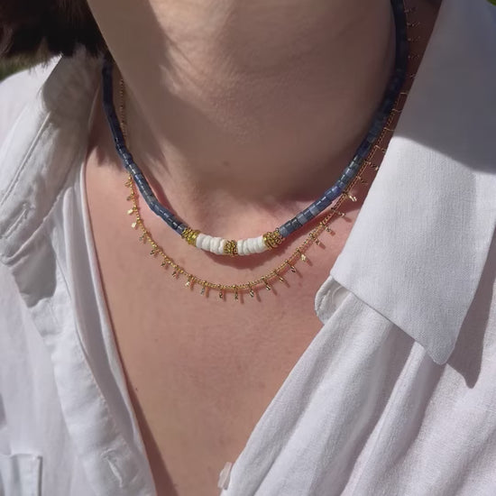 femme portant deux colliers en perles doré et bleu
